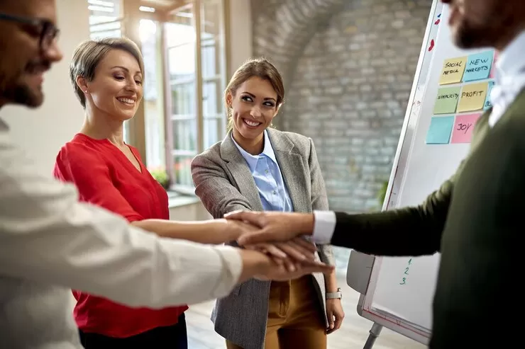 Equipe de negócios fazendo um "high-five" em equipe para celebrar o bom desempenho da equipe.