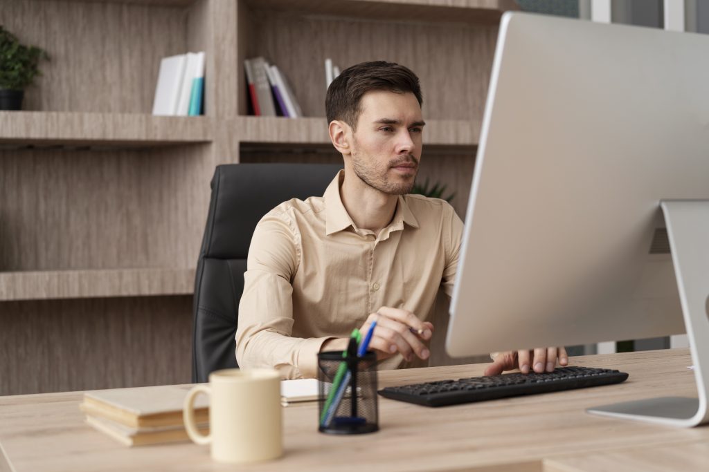 Um homem está sentado em frente ao computador, ele está montando um plano de carreira.