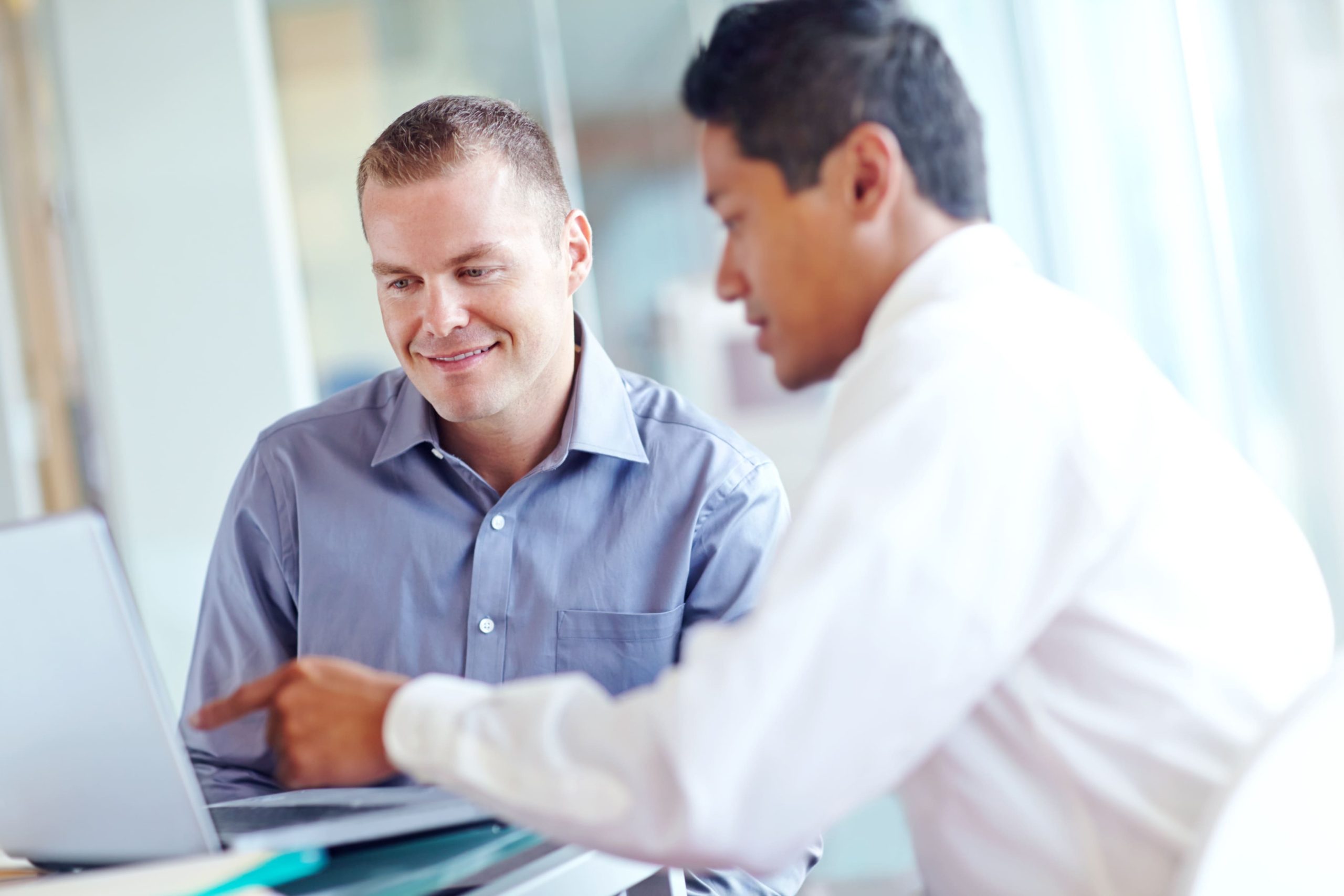 O foco da imagem está em um homem loiro, ele está sorrindo enquanto conversa com um homem a sua frente. A imagem representa o momento de alinhamento do pdi