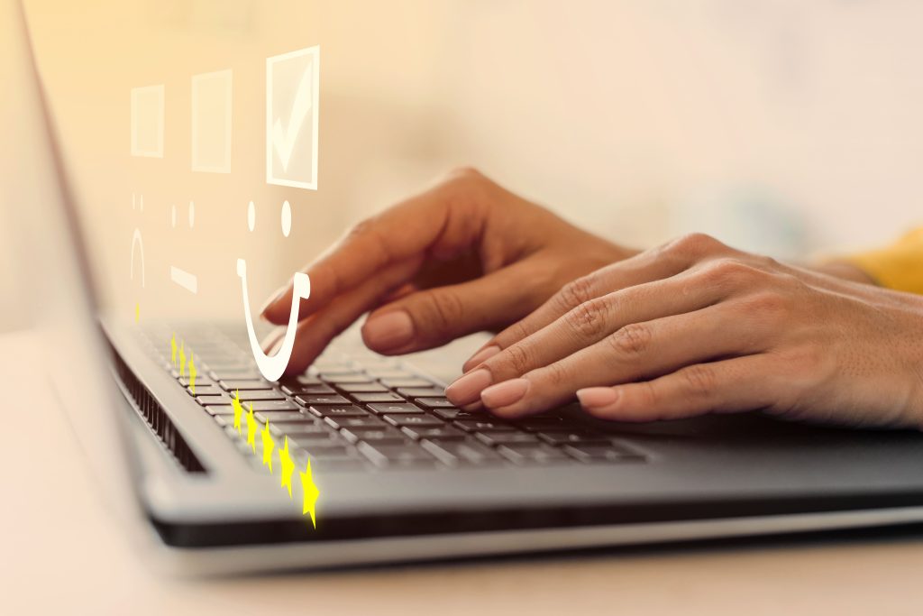 Pessoa digitando em um notebook com ícones de avaliação e estrelas na tela, representando coleta de feedback para avaliação de desempenho 180°