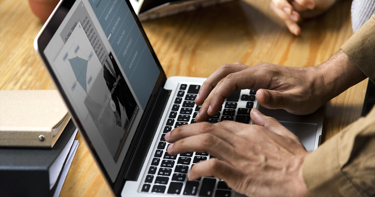 Pessoa digitando em notebook com dashboard na tela, aprendendo como descrever atividades do cargo de forma profissional