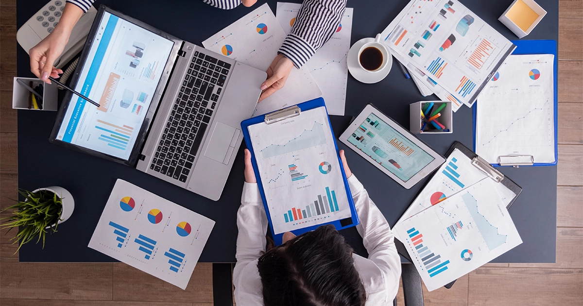 Profissional de RH analisando relatórios e ferramentas para descrição de cargo em mesa de trabalho.