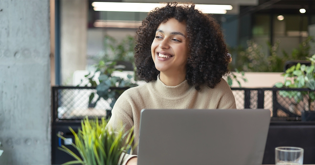 Colaboradora sorrindo ao usar notebook, ilustrando a aplicação do 9 box na avaliação de desempenho.