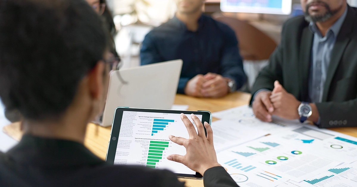 Equipe em reunião analisando gráficos e relatórios para a calibração da avaliação de desempenho.