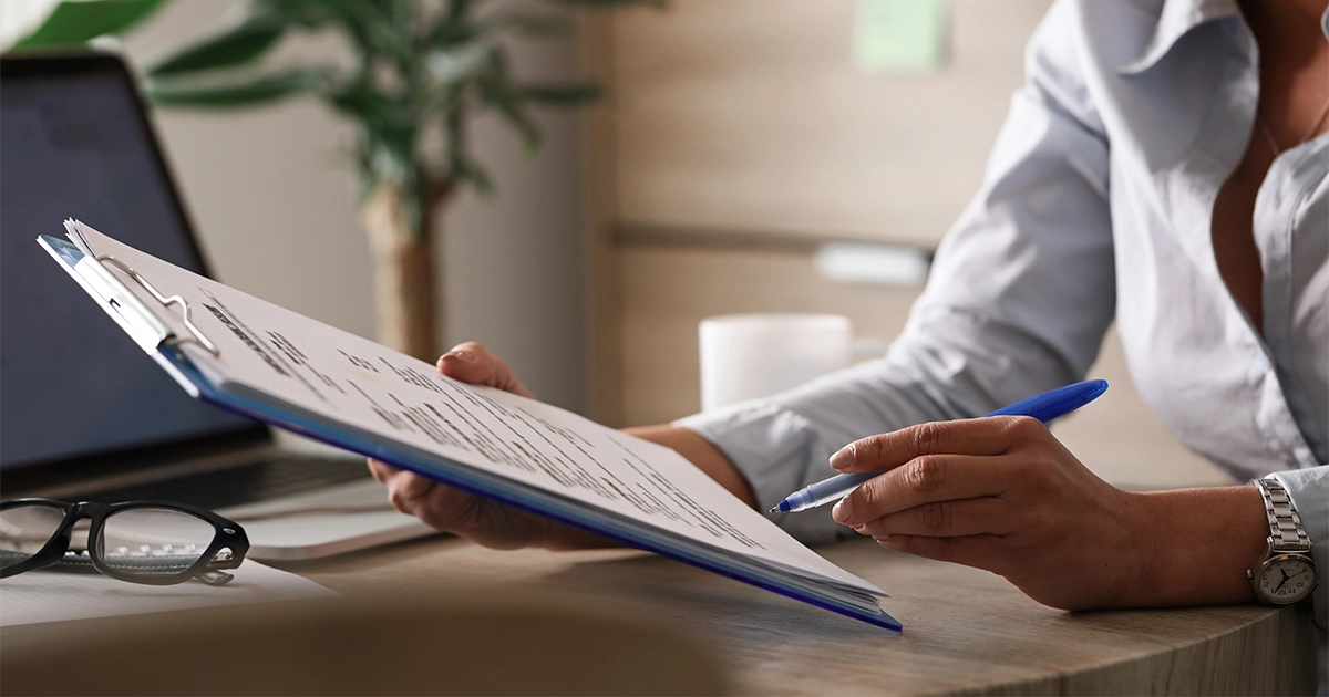 Profissional analisando documento de orçamento de treinamento na mesa de trabalho.