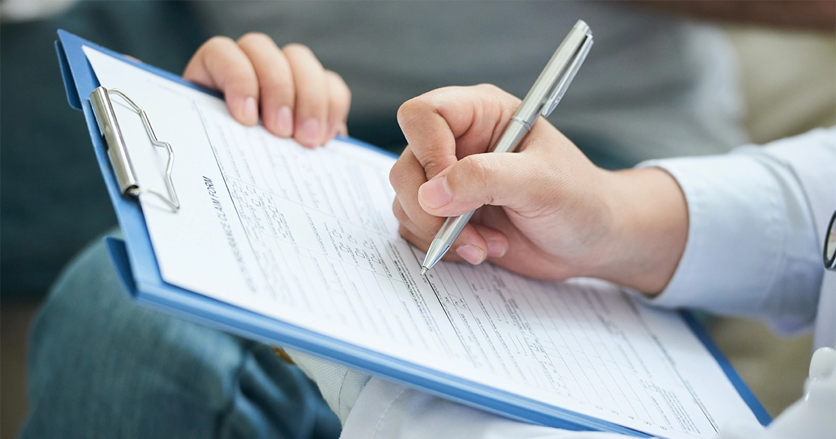 Pessoa preenchendo um checklist de auditoria de treinamentos em uma prancha com caneta.
