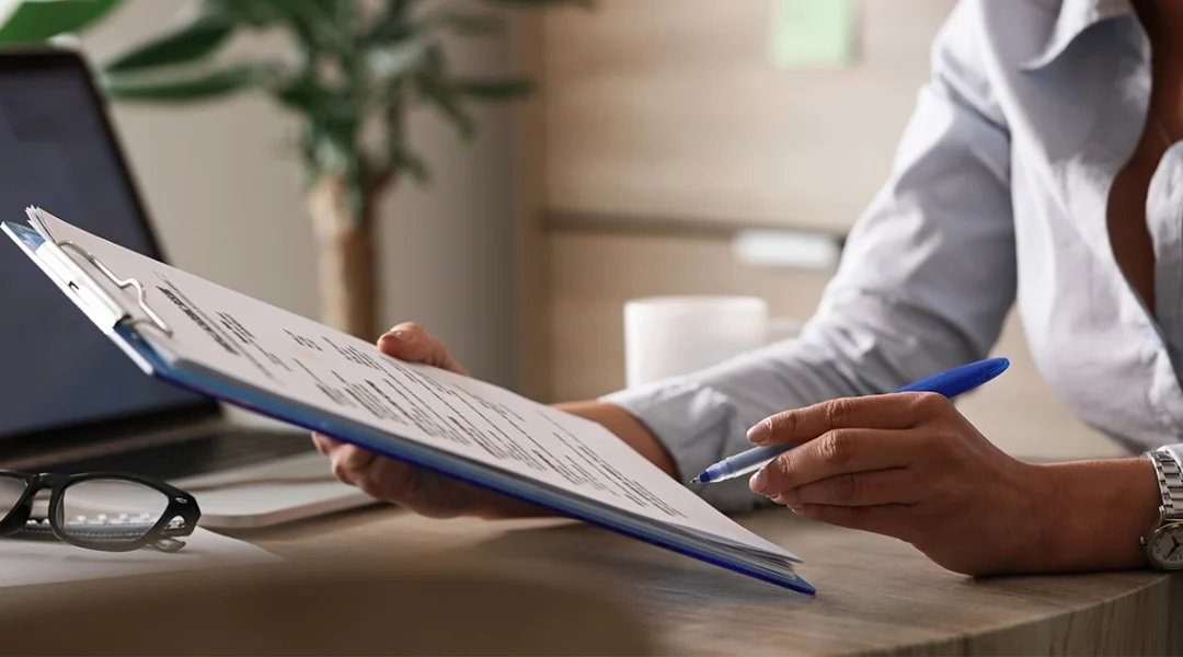 Profissional analisando documento de orçamento de treinamento na mesa de trabalho.