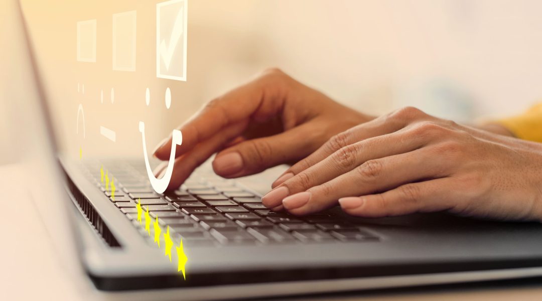 Pessoa digitando em um notebook com ícones de avaliação e estrelas na tela, representando coleta de feedback para avaliação de desempenho 180°