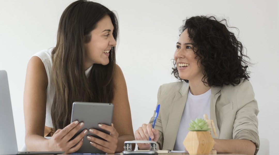 duas mulheres sorrindo finalizando um feedback contínuo