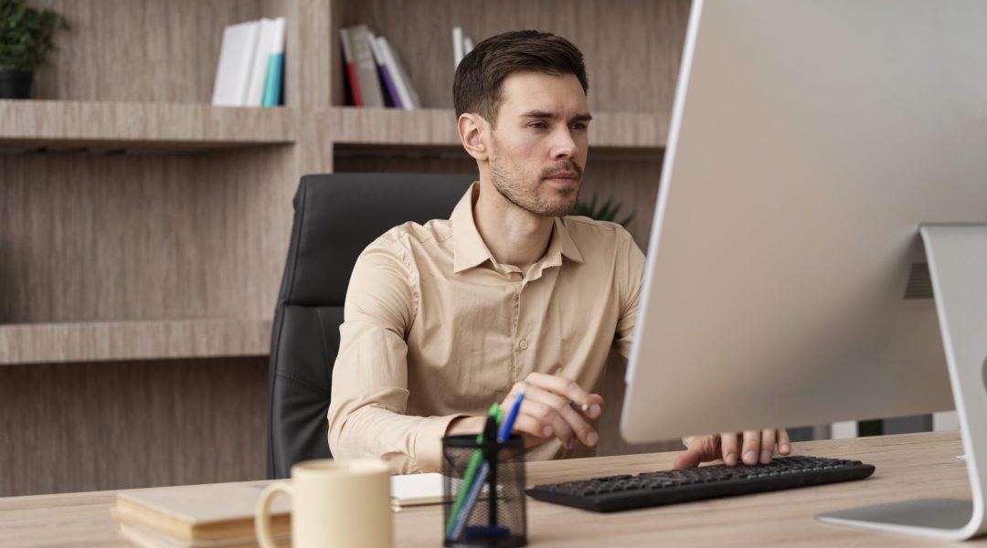 Um homem está sentado em frente ao computador, ele está montando um plano de carreira.