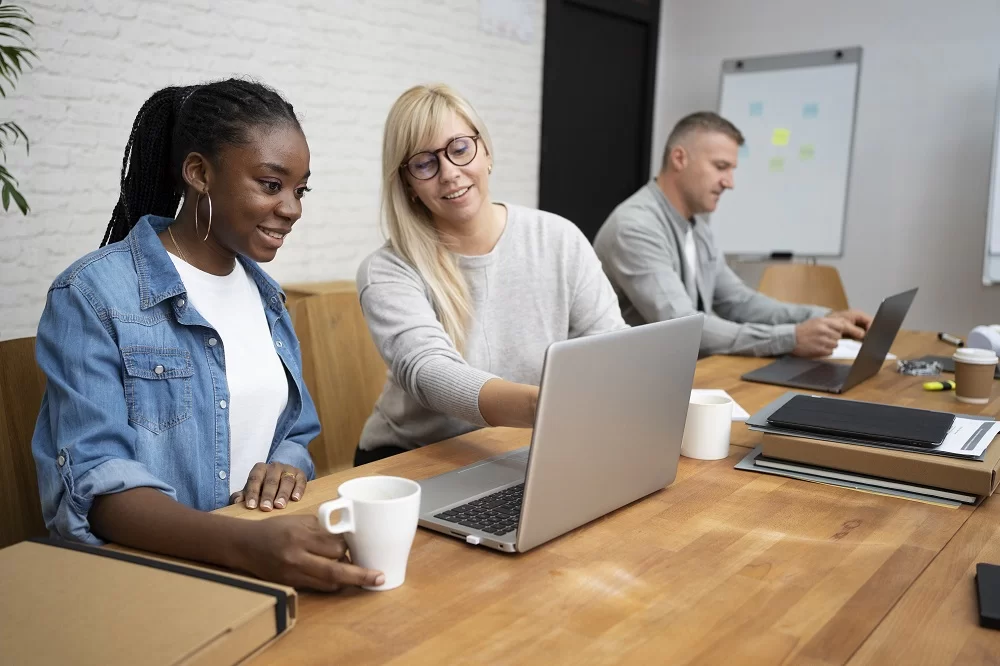 Duas mulheres estão sorrindo enquanto analisam os resultados da avaliação de comportamento.